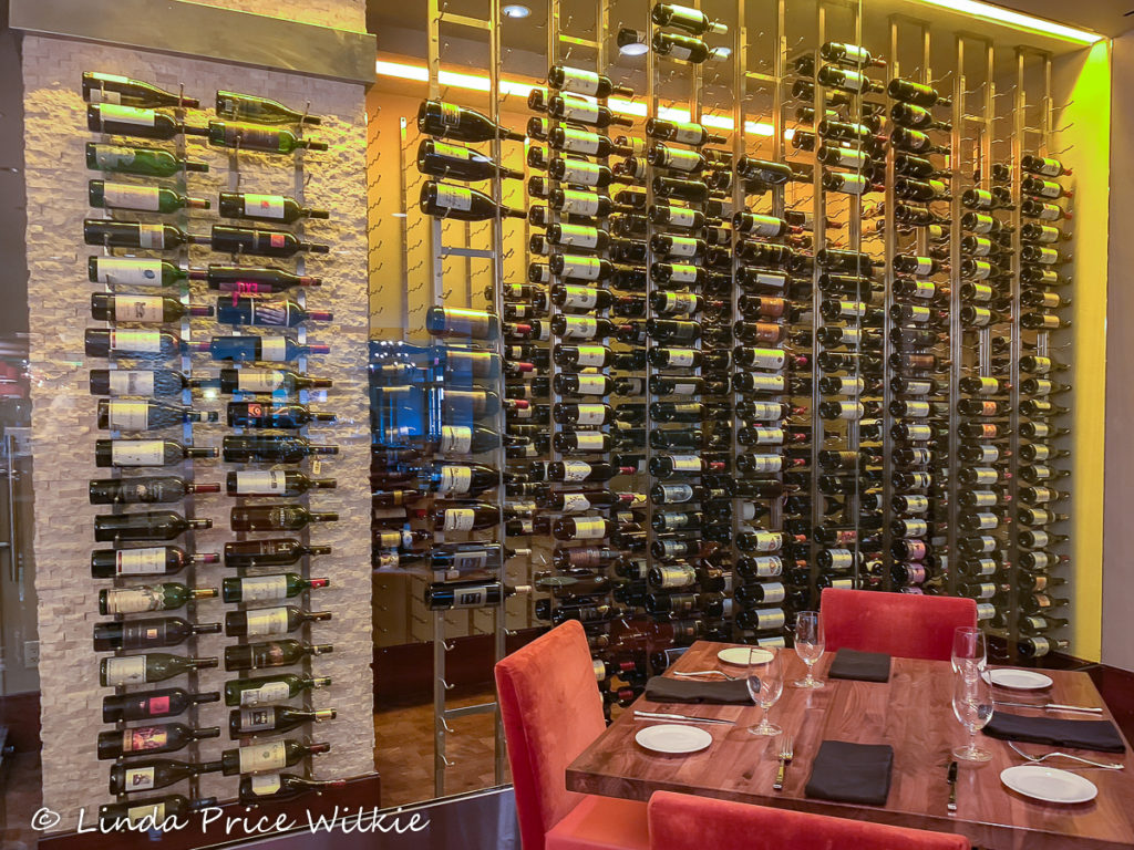 A photo showing Sustenio Restaurant's wine collection which is showcased behind glass walls in the dining area.