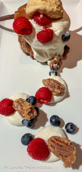 A photo of Mayan Chocolate cake, a complex dessert made with chocolate, whipped cream and caramel and served with Dulce de Leche ice cream, fresh berries and fiery spiced pecans.