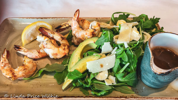 Key West grilled pink shrimp top the Tropicale Salad made with baby arugula, sliced avocado, hearts of palm, shaved Parmesan-Reggiano and creamy basalmic vinaigrette dressing on the side.