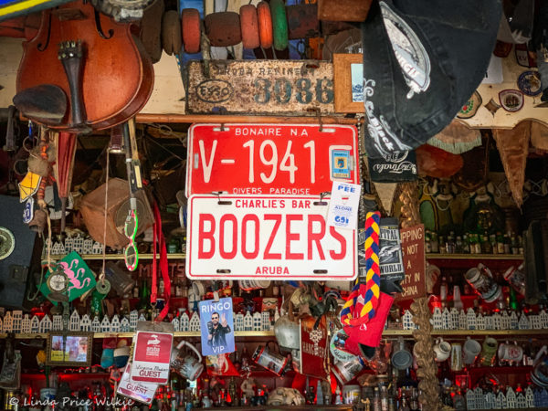 A photo of vintage Boozers and Bonaire license plates hanging from a wooden dowel in Charlie's Bar.